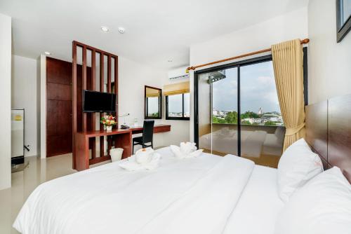 Un dormitorio con una gran cama blanca y una ventana en The Topaz Residence Phuket Town en Phuket