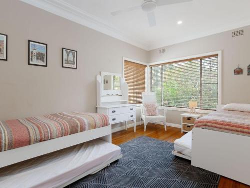 ein Schlafzimmer mit zwei Betten und einem Schreibtisch und einem Fenster in der Unterkunft Dutchies Haven, 11 Christmas Bush Ave - Pet friendly, large enclosed yard, air con and Wi-Fi in Nelson Bay