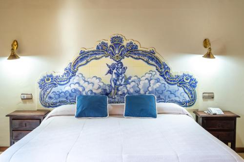 a blue and white bed with two blue pillows on it at Hotel Sao Joao De Deus by RIDAN Hotels in Elvas