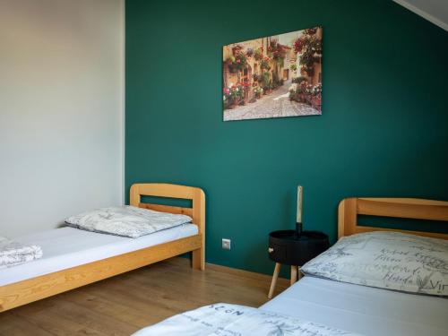 two beds in a room with a green wall at Hostel w ogrodzie in Grudziądz
