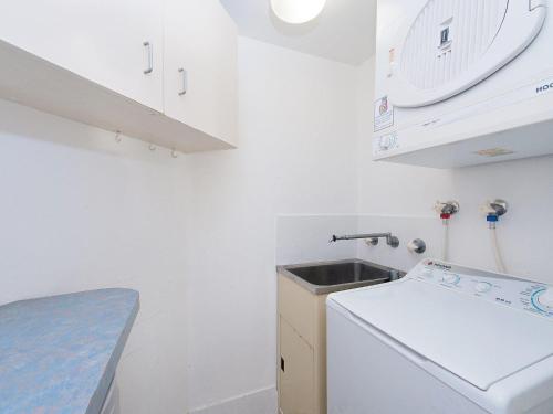 uma pequena cozinha branca com um lavatório e uma máquina de lavar louça em Fleetwood 2 spectacular views em Shoal Bay