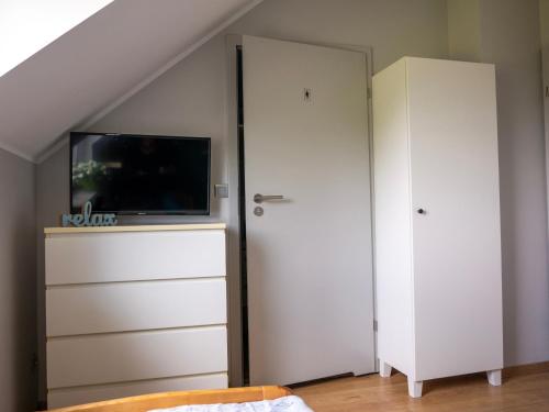 a bedroom with a tv and a closet with a dresser at Hostel w ogrodzie in Grudziądz