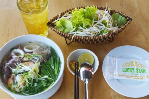 a table with two bowls of food and a salad at Lucky Star Ho Tram Hotel & Restaurant in Ho Tram