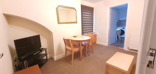 ein Wohnzimmer mit einem kleinen Tisch und einem TV in der Unterkunft Grace Apartments - Living Waters 1 in Ashford