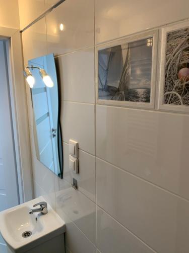 a white bathroom with a sink and a mirror at VULTOR Apartments in Wrocław