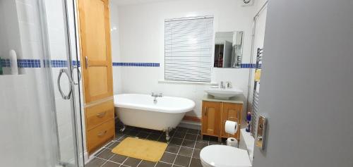 ein Badezimmer mit einer Badewanne, einem WC und einem Waschbecken in der Unterkunft Grace Apartments - Living Waters 1 in Ashford