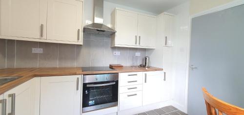 a kitchen with white cabinets and a stove at Grace Apartments - Living Waters 1 in Ashford