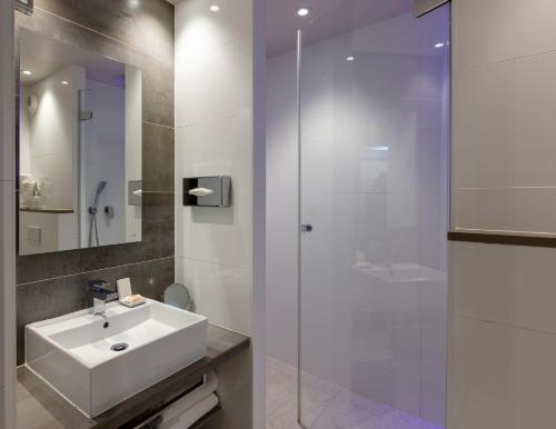 a bathroom with a sink and a glass shower at Best Western Plus Le Lavarin in Avignon