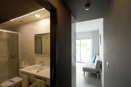 baño con lavabo, espejo y silla en Alsol Guatiza, en Playa del Inglés