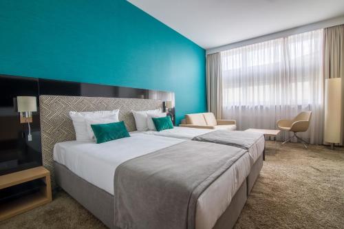 a bedroom with a large bed and a blue wall at Hotel Bażantowo Sport in Katowice