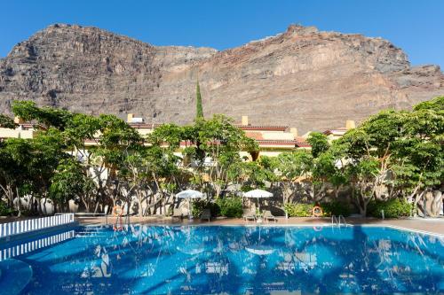 a large swimming pool with a mountain in the background at Residencial El Llano in Valle Gran Rey