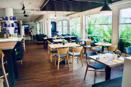 un restaurant avec des tables, des chaises et des fenêtres dans l'établissement ibis Strasbourg Aéroport Le Zénith, à Lingolsheim