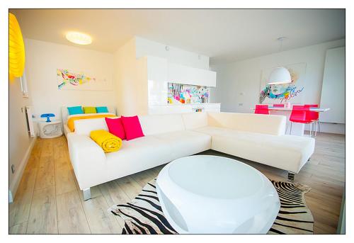 a living room with a white couch with colorful pillows at Zebra Baltic in Świnoujście