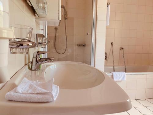 biała łazienka z umywalką i prysznicem w obiekcie Gasthaus Block w mieście Harkebrügge