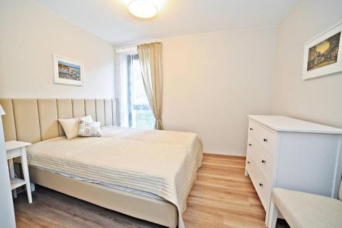 een kleine slaapkamer met een bed en een raam bij Deluxe Modern Apartment Victoria Residence by Grand Apartments in Sopot