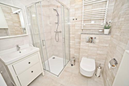 een badkamer met een douche, een toilet en een wastafel bij Deluxe Modern Apartment Victoria Residence by Grand Apartments in Sopot