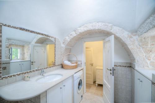 a bathroom with a sink and a mirror at Trulli La Piazzetta by Rentbeat in Cocolicchio