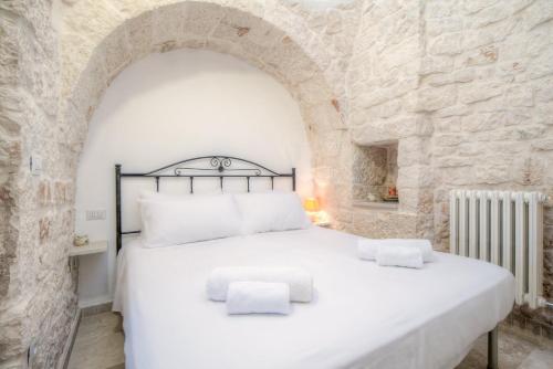 a bedroom with a white bed in a stone wall at Trulli La Piazzetta by Rentbeat in Cocolicchio