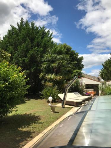 a pool with benches and a palm tree in a yard at La Diguinerie in Prignac