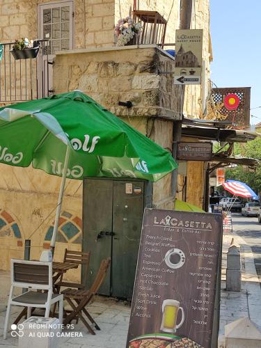 a green umbrella and a table and chairs on a street at La Casetta in Nazareth