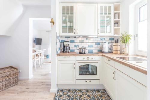 a kitchen with white cabinets and a rug at Fährhaus Sellin Haus am See in Ostseebad Sellin