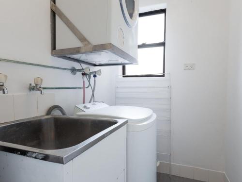 Una pequeña cocina con fregadero y lavadora. en Intrepid 13 fantastic unit with stunning water views, en Nelson Bay