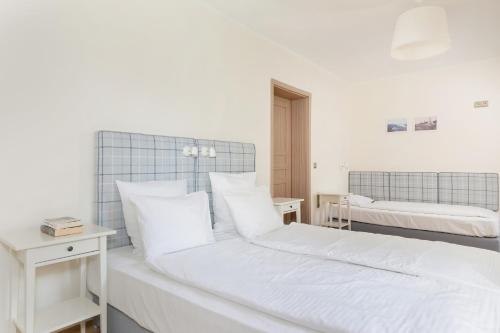 1 dormitorio con 2 camas y almohadas blancas en APARTAMENTY STARE SARBINOWO, en Sarbinowo