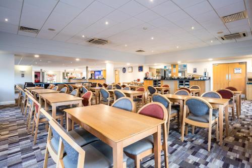 a dining room with wooden tables and chairs at Holiday Inn Express Stafford, an IHG Hotel in Stafford