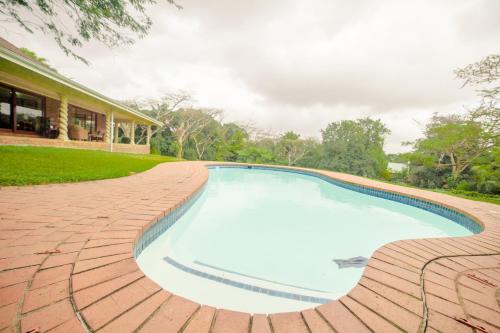 una piscina en una pasarela de ladrillo alrededor de una casa en Birds of Paradise B&B, en Eshowe