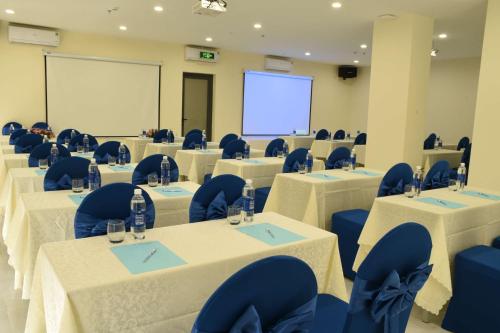a conference room with tables and chairs and a screen at Lucky Star Ho Tram Hotel & Restaurant in Ho Tram