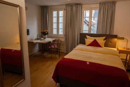 1 dormitorio con cama, mesa y espejo en Hotel Goldener Falke en Heidelberg