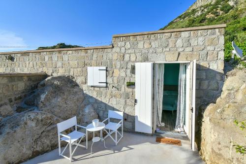 two chairs and a table in front of a stone building at Tenuta C'est la Vie in Ischia