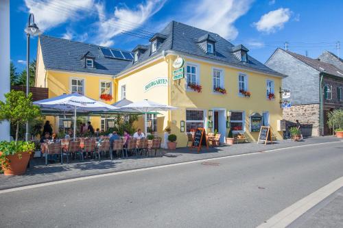 a group of people sitting at tables in front of a yellow building at Hotel zur Post in Mülheim an der Mosel