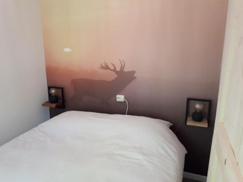 a bedroom with a bed with a deer silhouette on the wall at Huisje Koolmees park Hoefbos Otterlo in Otterlo