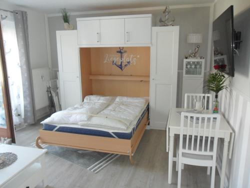 a bedroom with a bed with white cabinets and a table at Seemannskiste in Grömitz