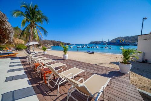 a row of chairs on a wooden deck next to a beach at Hotel Marina Resort & Beach Club in Santa Cruz Huatulco