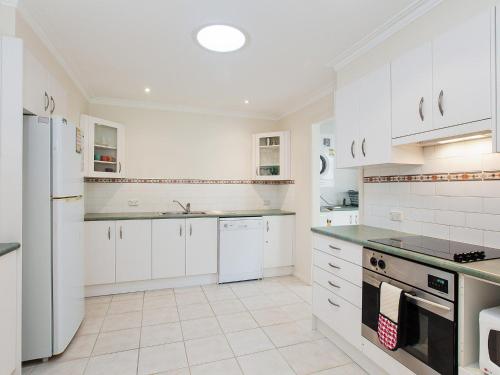a white kitchen with white cabinets and appliances at Happy Tails pet friendly air conditioned in Corlette