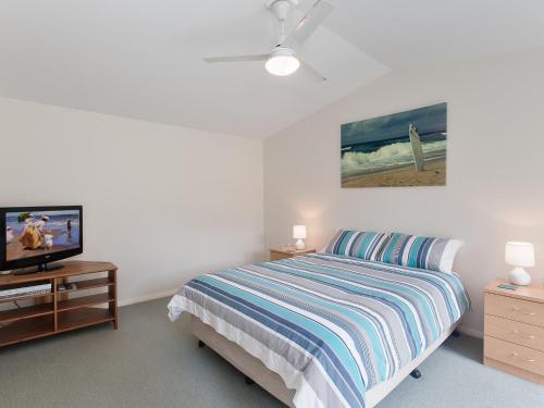 Schlafzimmer mit einem Bett und einem Flachbild-TV in der Unterkunft Happy Tails pet friendly air conditioned in Corlette