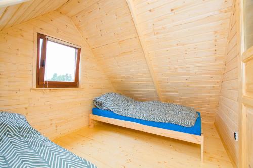 a small room with a bed in a wooden cabin at Domki KARO in Rowy