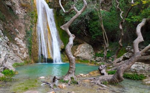 a waterfall and trees in front of a pool of water at ilias appartements tsaprounis in Elliniká