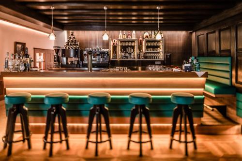a bar with green stools in front of a counter at Hotel Haus am Hang in Caldaro