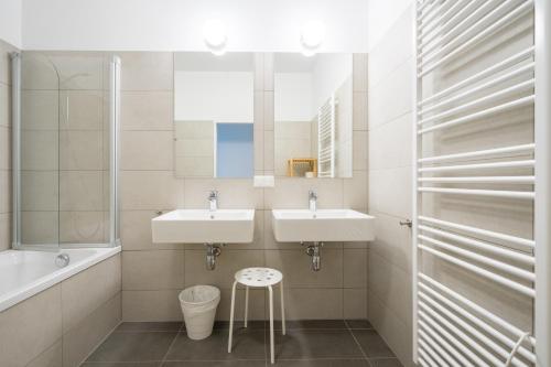 a bathroom with two sinks and a tub and a stool at FeelGood Apartments GreenLiving | contactless check-in in Vienna