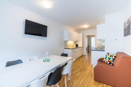 a kitchen and living room with a white table and chairs at FeelGood Apartments GreenLiving | contactless check-in in Vienna