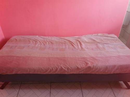 Bett in einem Zimmer mit einer rosa Wand in der Unterkunft CASA das ORQUÍDEAS NOTA 1000 in Teresina