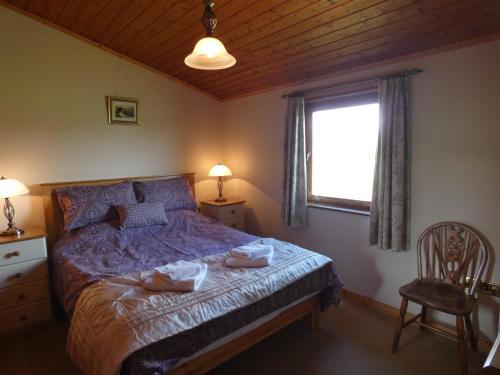 a bedroom with a bed with a purple comforter and a window at Chestnut Lodge in Pilling