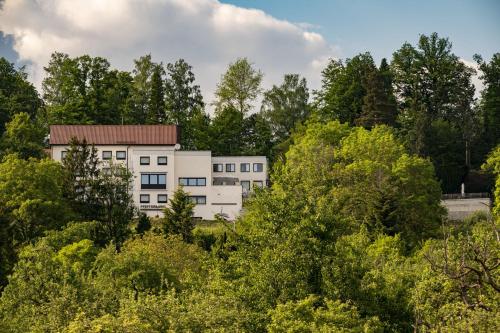 um edifício branco no meio das árvores em Hotel Pfefferburg em Schönaich