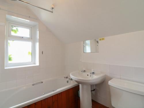 a white bathroom with a sink and a bath tub and a sink at The Stable in Bude