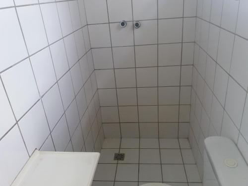 a white tiled bathroom with a toilet and a sink at CASA das ORQUÍDEAS NOTA 1000 in Teresina