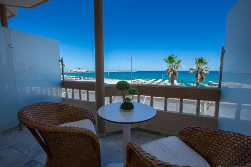 einen Balkon mit Tisch und Stühlen sowie Strand in der Unterkunft Theo Beach Hotel Apartments in Rethymno