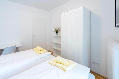 a white bedroom with white cabinets and two towels at FeelGood Apartments GreenLiving | contactless check-in in Vienna